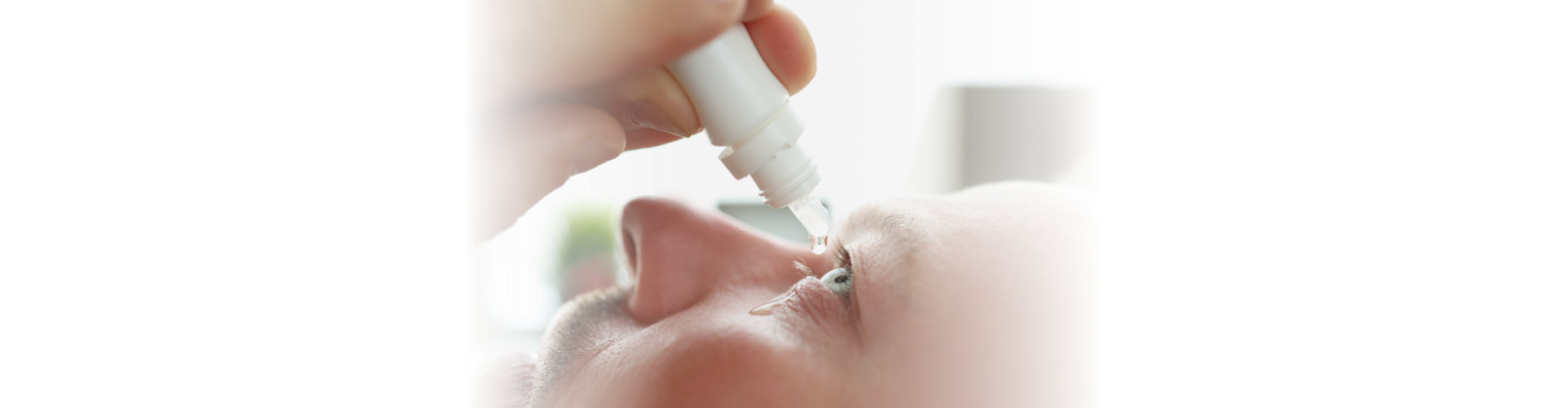 Man dripping antibacterial drops into his eye closeup